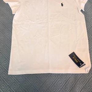 Vit t-shirt från Polo Ralph Lauren - Vit t-shirt från Polo Ralph Lauren i klassisk modell med korta ärmar. T-shirten har den ikoniska broderade loggan i svart på bröstet. | Skick: 10 / 10, prislappen kvar! | Nypris: ~ 800 | Vårt pris: 499 | Storlek: S | Tveka inte att skicka ett meddelande! Priset är förhandlingsbart!