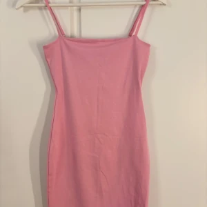 Rosa kort klänning från Zara - Supersöt rosa klänning från Zara med smala axelband och rak passform. Klänningen är enkel och stilren, perfekt för dig som gillar en clean look. Tillverkad i mjuk bomull som känns skön mot huden. Säljes med tag kvar! Aldrig använt den, köptes och passade inte alls mig🙂‍↕️
