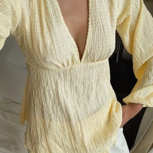 Ljusgul blus med v-ringning - Supersöt ljusgul blus i  bomull med  v-ringning fram och öppen rygg med knytband. Ääälskar denna men har tröttnat på färgen tyvärr. Från NAKD, storlek S. Helt oanvänd💛🍂