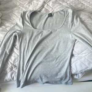 Ljusgrå långärmad topp  SHEIN - En basic ljusgrå långärmad topp från  Shein med rundad, djup urringning. Tunn och mjuk i bomullsmix, perfekt att styla med jeans eller kjol. Enkel och stilren design som funkar till många looks. Använt den en gång, är ren inga fläckar ingenting!