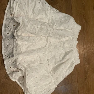 Vit kjol - Supersöt vit kortkjol från Vintage Dressing med broderade blommor och elastisk midja. Storlek S/M. Aldrig använd