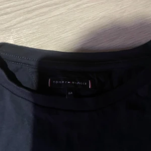 Svart t-shirt Tommy Hilfiger - Svart t-shirt från Tommy Hilfiger med klassisk rund hals och liten broderad logga på bröstet. Enkel och stilren design som passar till allt. Tillverkad i mjuk bomull för skön känsla hela dagen.