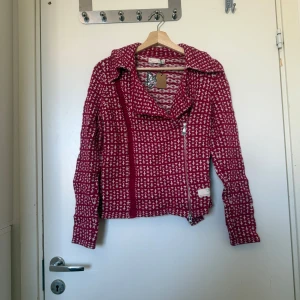 Röd stickad bikerjacka Odd Molly - Säljer en röd och vit stickad kofta från Odd Molly med coolt mönster och sned dragkedja. Kofta har bred krage, lång ärm och är i mjukt stickat material. Perfekt för dig som vill sticka ut med en unik och färgglad look. Storlek 2 som enligt deras storleksguide motsvarar en storlek M. Mer använd men fortfarande fint skick. Kan finnas små tecken på användning. 