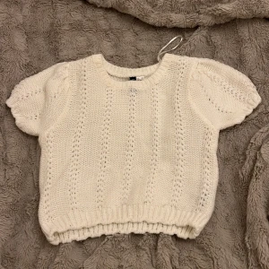 Vit stickad tröja med puffärm H&M - Supersöt vit stickad tröja från H&M med korta puffärmar och ribbad kant nedtill. 