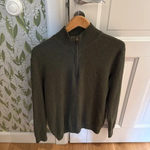 Olivgrön stickad tröja Polo Ralph Lauren - Snygg olivgrön stickad tröja från Polo Ralph Lauren med half zip och hög krage. Tröjan har långärmade ribbade muddar. Skick 7/10 använd och lite nopprig!