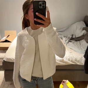 Vit quiltad jacka  - Säljer en vit  jacka  med snygg struktur och dragkedja framtill. Jackan har rund halsringning, lång ärm, använd fåtal gånger.