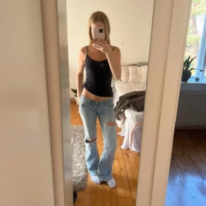 Ljusblå bootcut jeans  - Säljer ett par ljusblå bootcut jeans från Miss Sixty med låg midja och slitna detaljer på knäna. Jeansen har klassiska bakfickor med broderi och är tillverkade i jeansmaterial. Perfekta för dig som gillar en avslappnad och trendig look. Storlek w26 L34. De är lite slitna vid grenen, men inget som syns på. De knäpps med två knappar, alltså ingen dragkedja. 