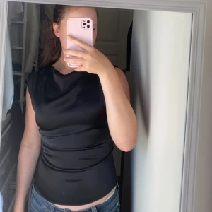 Svart satintopp😍🥂 - PRIS KAN DISKUTERAS. Snygg svart blus i satin, kort ärm med dragkedja🖤Perfekt topp för finare tillfällen eller fest🥰 använd 1 gång, är som ny! den är för liten för mig och säljer därför, Skickar samma dag som köp🫶🏻