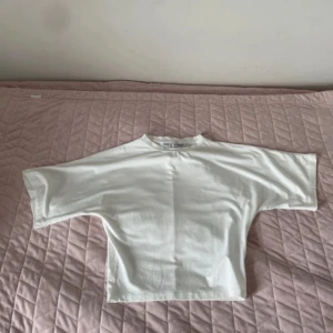 Vit croppad t-shirt med loose fit - Säljer en vit croppad t-shirt med loose passform och korta ärmar. T-shirten har en enkel design med rund hals och är gjord i mjuk bomull. Perfekt för dig som gillar en avslappnad och stilren look.