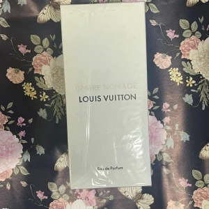 Louis Vuitton Ombre Nomade Parfym 100ml - *KVITTO FINNS*100 ml Lyxig parfym från Louis Vuitton, Ombre Nomade, i elegant vit kartong med svart och guld text. Eau de Parfum, tillverkad i Frankrike. Förpackningen har klassisk LV-logga och exklusiv känsla. Perfekt för dig som gillar exklusiva dofter och snygg design.