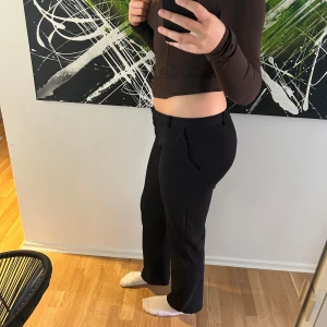 Svarta lågmidjade kostymbyxor  - Jag säljer ett par fina lågmidjade svarta kostymbyxor med rakpassform och klassiska fickor längst fram. Byxorna har även bälteshällor och stängs med en knapp samt dragkedja. Byxorna är använda, och har lite slitage vid sidan av benen, men det är inget som syns! Dessa kostymbyxorna är perfekta för en stilren och clean look, passar både till en utekväll och vardagligt💕