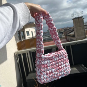 Virkad väska i ljusrosa/vit - Hemmavirkad handväska, gjord i t-shirtgarn som är gjort av textilindustrins tygöverskott.   Mått: ca 22cm bred, 15cm hög och 38cm hög (inklusive handtag)