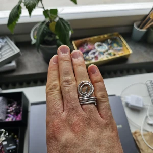 Handgjord Silvrig Spiralring I Metalltråd - Cool ring i silverfärgad metalltråd med en unik spiralformad design. Ringen har flera varv runt fingret och en stor spiral på ovansidan som ger ett edgy och handgjort intryck. Ringen är i aluminium och är 18.5 mm