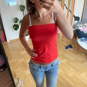 Röd tubtopp - Säljer denna röda tubtopp med enkel, rak passform. Dubbelvikt tyg vid bysten, toppen är ärmlös och har en tight fit som sitter snyggt mot kroppen. Säljer då det inte längre är min stil 🩷