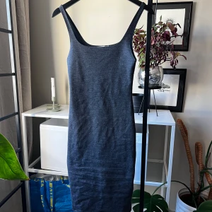 Mörkgrå tight klänning från Zara - Tight, ärmlös klänning från Zara Trafaluc i mörkgrått. Modellen är midilång med smala axelband och en liten slits bak. Mjuk och stretchig bomullsblandning som sitter snyggt på kroppen. Perfekt för dig som gillar minimalistisk stil.