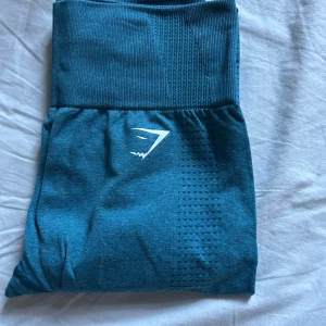 Blå leggings från Gymshark - Supersnygga blå leggings från Gymshark med hög midja. Stretchigt och mjukt material som sitter tight och bekvämt, perfekt för träning eller chill. Diskret logga under midjan och på vristen. De är knappt använda. Hör gärna av er vid minsta lilla fråga! Vänligen se de andra annonserna om ni är intresserade av paketpris.