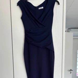 Mörkblå klänning från bubbleroom - Snygg mörkblå klänning från bubbleroom i figurnära modell med draperad midja och v-ringad omlott upptill. Endast använd en kväll💗