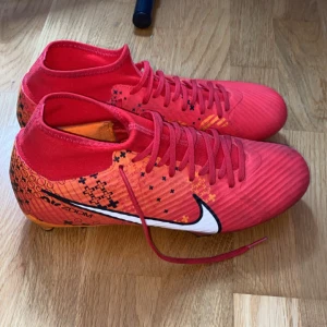 Röda Nike CR7 fotbollsskor - Snygga röda Nike CR7 fotbollsskor med coolt grafiskt mönster i orange och svart. Är använda typ en gång så invändigt bra skick.
