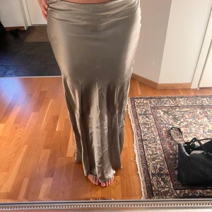 långkjol i satin - Supersnygg  långkjol i satinmaterial. Kjolen har en figurnära passform upptill och faller snyggt längs benen. Perfekt för dig som vill ha en stilren och trendig look.