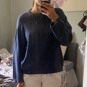 Mörkblå stickad tröja - En enkel och snygg mörkblå stickad tröja med rund halsringning och långärmad passform. Tröjan har en lite loose fit och är perfekt att slänga på sig när det är kyligt ute. 