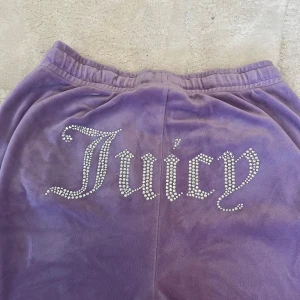 Lila Juicy Couture byxor S - Lila mjukisbyxor från Juicy Couture med strassdetaljer. Byxorna har raka ben. Få defekter finns tyvärr (syns i bilderna) men inga rhinestones saknas! 