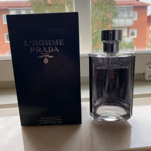 Prada L'Homme 150ml - Prada L'Homme i en elegant, genomskinlig glasflaska med silverfärgad metallkork. Flaskan rymmer 150 ml och kommer med original svart förpackning med silverdetaljer. En klassisk och stilren herrdoft från Prada Milano. Kvitto finns. Skriv vid minsta lilla fundering. 1350 nypris.
