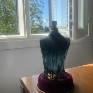 Jean Paul Gaultier Le Beau Le Parfum - Snygg parfymflaska formad som en manlig torso i mörkblått glas med gulddetaljer och en dekorativ guldblad-accent. Kommer med originalförpackning i turkos metall och röd sammetsbas. En ikonisk och lyxig doft som sticker ut i hyllan säljer denna för den var inte min lukt nu jag blind buy denna. Denna är väldig god men Jag gillar mer elixir dofter. Använd 10-25 sprej har kanske 122ML kvar.