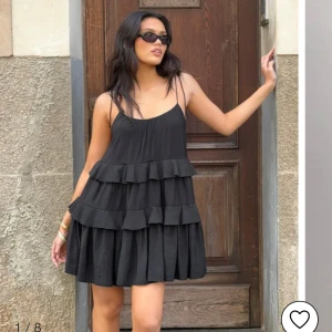 Svart volangklänning med öppen rygg - Supersöt svart kortklänning med volanger och tunna axelband som knyts på axlarna. Klänningen har en luftig passform och öppen rygg med smala band. Nypris 399kr på nellys hemsida. Aldrig använt och har lapparna kvar.