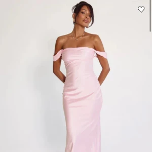 Ljusrosa balklänning - Superfin ljusrosa balklänning i satin som är offshoulder. Perfekt för bal eller student. Materialet är glansigt och ger en lyxig känsla. Oanvänd och inte ens provad då den levererades för sent. Kostade 1500 kr inklusive frakt.