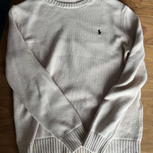 Beige stickad tröja från Polo Ralph Lauren - Snygg beige stickad tröja från Polo Ralph Lauren. Storlek L men passar M. Använd en gång