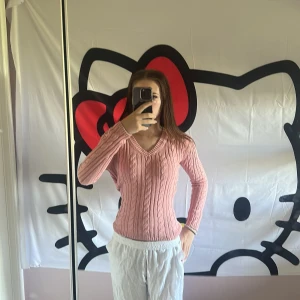 Rosa kabelstickad tröja med v-ringning - Hej, säljer denna Supersöta rosa kabelstickad tröja från Gant med v-ringad hals och figurnära passform. Modellen är 167cm. Och endast 429kr!!! Ny pris runt 1,300kr🤩 inga defekter och den är praktiskt taget ny! Tröjan har långa ärmar och klassiska stickade detaljer som ger en preppy vibe. Perfekt att styla med jeans eller kjol för en chill look.       Skriv vid minsta fundering!!!