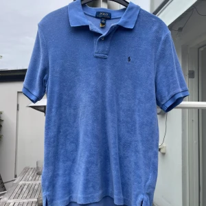 Blå frotté pikétröja från Polo Ralph Lauren - Säljer en blå frotté pique från Polo Ralph Lauren med korta ärmar och krage. Tröjan har broderad logga på bröstet . Perfekt för en chill och stilren look. Använd en gång då jag behövde en storlek större. Original pris 949