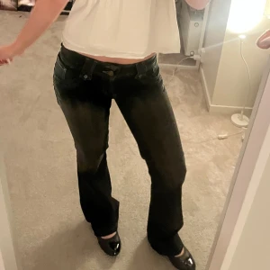 Svarta bootcut jeans - Galet snygga svarta bootcut jeans från Sancers med slitningar och broderade detaljer på bakfickorna. Jeansen är lågmidjade och köpta från en vintagemarknad💕 kom privat för frågor eller fler bilder❣️storlek står ej men skulle säga w25L30-32. Priset kan diskuteras💓