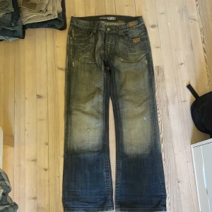 Blå bootcut jeans från SMOG - Blå/gröna super baggy jeans från smog 😆 fult med detaljer och distressing jeansen är nästan oanvända 