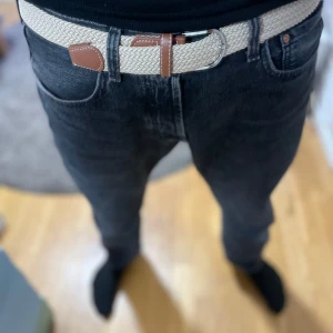 Beige flätat bälte med bruna detaljer - Snyggt beige flätat bälte med bruna skinn-detaljer och silverfärgat spänne. Perfekt accessoar för att lyfta din outfit med en stilren touch. Passar till jeans eller chinos. Aldrig använt! Nytt skick!