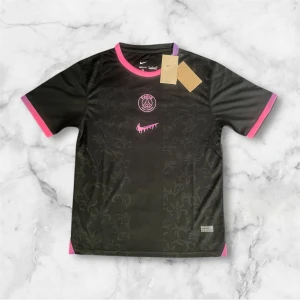 Svart PSG fotbollströja med rosa detaljer - Säljer en svart Paris Saint-Germain fotbollströja från Nike med rosa och lila detaljer vid krage och ärmslut. Tröjan har PSG-logga och ett rosa Nike-märke på bröstet samt diskret blommönster i tyget. Perfekt för fotbollsfans!
