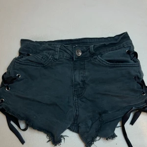 Svarta jeansshorts med snörning  - Snygga svarta jeansshorts från Rue med fransig kant och cool snörningsdetalj i sidorna. Köpt i Frankrike, den finns inte längre att köpa eftersom det är en limited edition plagg. Shortsen är lågmidjade och jätte fina passar xs och xxs.Pris kan såklart diskuteras(tänk på att den är limited edition)🤍