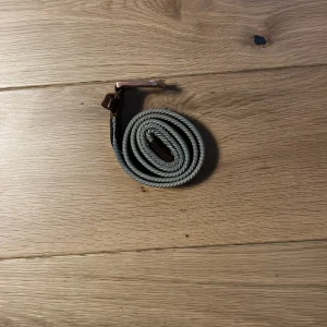 Grått flätat bälte med bruna skinn-detaljer från Oscar Jacobson - Säljer ett stilrent grått flätat bälte från Oscar Jacobson med bruna skinn-detaljer och metallspänne. Perfekt accessoar för att lyfta din outfit med en klassisk touch. Bältet har en elegant och tidlös design.