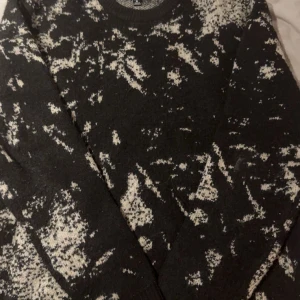 Svart och vit mönstrad stickad tröja - Säljer en stickad tröja i svart med vitt abstrakt mönster. Tröjan har rund halsringning och långa ärmar. Perfekt för dig som gillar en unik och trendig stil.