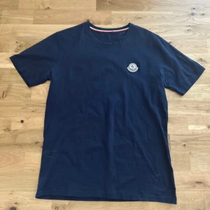 Moncler T-shirt - Säljer en blå Moncler T-shirt i mycket bra skick. Använd sparsamt, inga skador eller fläckar. Storlek: M                                                                                Pris: 199kr priset är fast