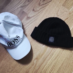 Vit keps från Hugo Boss - Stone Island mössa i stl ungdom,,svart Vit keps från Hugo Boss med tydlig logga framtill och justerbart spänne baktill i metall.....säljer båda ihop för 400kr