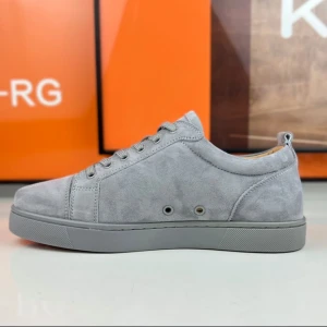 Gråa Christian Louboutin i mocka med röd sula - Snygga grå sneakers i mocka med klassisk snörning och rund tå. Skorna har en unik röd sula och diskreta metalldetaljer på sidan. Perfekta för dig som vill ha en stilren men ändå iögonfallande look.