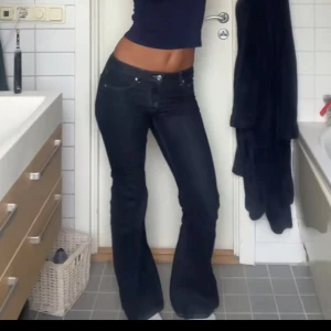 Mörkblå lågmidjade bootcut jeans - Säljer ett par mörkblå bootcut jeans med klassisk femficksdesign och kontrastsömmar. Jeansen har normal passform och är tillverkade i denim med lätt stretch. Perfekta för dig som gillar en tidlös look med lite utsvängda ben. Köpta för 500kr
