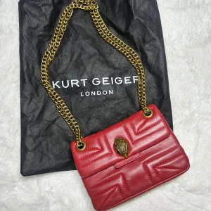 Kurt geiger väska mini kensington crossbody  - Kurt geiger väska, mini modellen i läder. Lite mer mörkröd i verkligheten. Dustbag medföljer. Superfint skick. Svår att få tag i då den inte säljes längre. Går att bära crossover eller på axeln. Kan skicka fler bilder på detaljer i dm. Köp sker via köp nu, jag postar inom 24h. Kvar tills markerad såld 