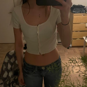 Vit croppad ribbad topp med knappar - Säljer en vit croppad topp med korta ärmar och knappar fram till. 