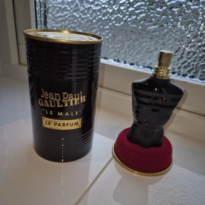 Jean Paul Gaultier Le Male Le Parfum - Säljer en lyxig parfym från Jean Paul Gaultier, Le Male Le Parfum, 75ml😁👌 Flaskan har en unik design i form av en svart torso med gulddetaljer, och kommer med originalförpackningen i svart och guld✅️ Doften är intensiv och maskulin😍 Flaskan har ungerfär 65 ml kvar och har förvarats i bra temperatur och miljö🤩✅️ Pris kan diskuteras!💲