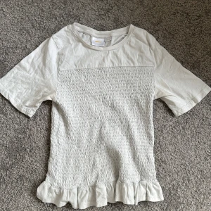 Vit topp med volangkant - Säljer en söt vit topp!!! Den är ifrån Gina Young och har storleken 158-164💓 säljer den pga inte min stil, och andvänds inte längre… jätte bra skick och har andvänds ett fåtal gånger 💕