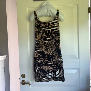 Leopardmönstrad kortklänning från Gina Tricot - Säljer en snygg kortklänning från Gina Tricot med leopardmönster i svart, beige och brunt. Klänningen är ärmlös med breda axelband och har en tight passform. Perfekt för dig som vill sticka ut med ett djurmönster!