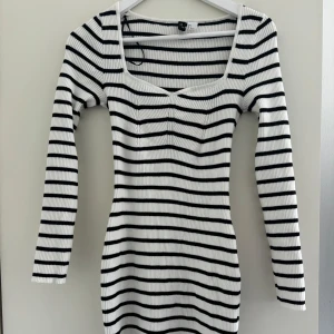 Randig ribbad klänning från H&M  - Säljer en vit och svart ribbad klänning från H&M Divided med lång ärm och fyrkantig ringning. Klänningen är i mycket bra skick och storlek S.