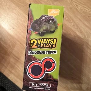 Dinotrack Express Dinosaur Track - Rolig och kreativ dinosauriebana med flexibla spår och dinosauriefigurer. Setet innehåller gröna spårdelar, broar och tillbehör för att bygga olika banor. Passar barn från 3 år och uppåt. Perfekt för dig som gillar dinosaurier och byggleksaker.